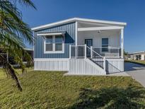 Single-wide home with blue and white siding, covered porch, and landscaped lawn at 127 Nautical Dr, North Port, FL 34287