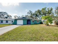 Green house exterior with white garage door and landscaping at 1323 Karen Dr, Venice, FL 34285