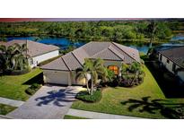 Single-Gathering home with tile roof, landscaping, and a view of the water at 20314 Passagio Dr, Venice, FL 34293