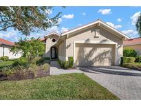 Tan single-story home with a two-car garage and landscaped lawn at 115 Avalini Way, North Venice, FL 34275