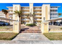 Beautiful building exterior with balconies, palm trees, and a covered parking area at 1200 Tarpon Center Dr # 108, Venice, FL 34285