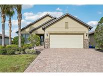 Tan one-story house with a two-car garage and landscaped front yard at 13280 Esposito St, Venice, FL 34293