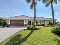 Single-story home with a brown garage door, landscaping, and palm trees at 2269 Lakewood Dr, Nokomis, FL 34275