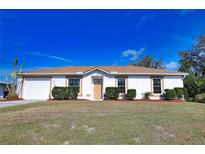 White house with brown roof, landscaping, and a two-car garage at 7148 Totem Ave, North Port, FL 34291