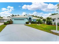 Light teal house with a two-car garage and well-manicured lawn at 1384 Clubview Ct, Venice, FL 34292
