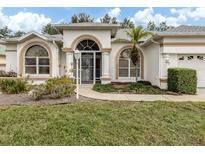 White one-story house with arched entryway, landscaping, and a two-car garage at 470 Bermuda Isles Cir, Venice, FL 34292