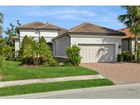 Single-story home with a tile roof, landscaped yard, and two-car garage at 5592 Semolino St, Nokomis, FL 34275