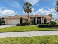 Tan house with tile roof, palm trees, and landscaped yard at 1579 Waterford Dr, Venice, FL 34292