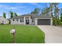 Single-story home with dark gray garage door and well-manicured lawn at 18055 Dublin Ave, Port Charlotte, FL 33948