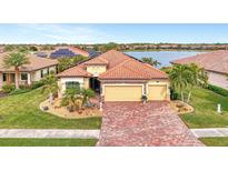 Two-story house with three car garage and brick driveway, near a lake at 20323 Granlago Dr, Venice, FL 34293