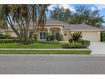 Single-story house with a tile roof, double door entry, and lush landscaping at 2144 Calusa Lakes Blvd, Nokomis, FL 34275