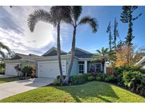 Single-story home with light blue exterior, two-car garage, and landscaped yard at 309 Pavonia Rd, Nokomis, FL 34275