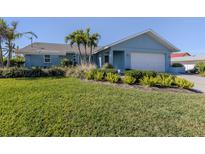 Light blue house with a well-manicured lawn and palm trees at 900 Osprey St, Venice, FL 34285