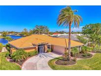 Tan house with tile roof, palm trees, and landscaped yard at 1815 Killdeer Ct, Venice, FL 34293