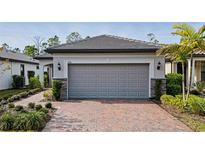 House exterior featuring a gray garage door, brick driveway and landscaping at 2751 Lavandula Ct, North Port, FL 34289