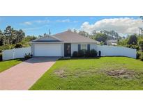 Newly constructed home with a white vinyl fence and a brick paver driveway at 5552 Guest Ter, Port Charlotte, FL 33981