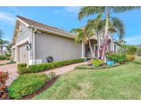 Tan house with tile roof, landscaping, and a three-car garage at 11409 Okaloosa Dr, Venice, FL 34293