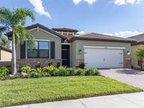 Single-story house with green exterior, landscaping, and a two-car garage at 11945 Lovegrass St, Venice, FL 34293