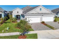 Two-car garage, gray exterior, landscaping, and a paved driveway at 12488 Palatka Dr, Venice, FL 34293