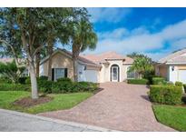 Tan two-story house with tile roof, white garage door, and landscaped yard at 13240 Guyana St, Venice, FL 34293