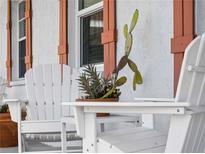 Inviting front porch with white chairs and potted plants at 1423 Avenida Del Circo # 1C, Venice, FL 34285