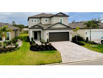 Beautiful two-story home featuring manicured landscaping, brick driveway, and a two-car garage at 1920 Sunset Preserve Way, Port Charlotte, FL 33953