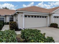 Exterior of a beige villa with a two-car garage and well-manicured landscaping at 1931 San Silvestro Dr, Venice, FL 34285