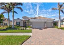 Single-story home with tile roof, two-car garage, and lush landscaping at 20175 Elegante Ct, Venice, FL 34293