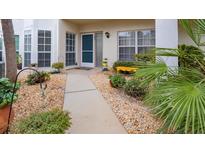 Inviting condo entrance with landscaped walkway, and a yellow bench at 400 Laurel Lake Dr # 105, Venice, FL 34292