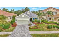 Single-story home with gray roof, light green walls, and a paver driveway at 12386 Sagewood Dr, Venice, FL 34293