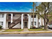 Two-story condo building with wood stairs and lush landscaping at 1640 Stickney Point Rd # 202, Sarasota, FL 34231