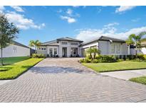 Two-story home with gray exterior, paver driveway, and manicured lawn at 19854 Bridgetown Loop, Venice, FL 34293