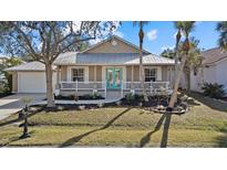 Tan house with teal front door, white porch, and landscaped yard at 205 Tortuga Dr, Nokomis, FL 34275