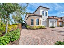 Exterior view of a two-story townhome with a brick driveway and landscaping at 23210 Banbury Way # 101, Venice, FL 34293