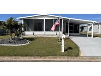 Single-wide mobile home with carport, screened porch, and landscaped yard at 28 Castaway Ct, North Port, FL 34287