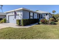 Charming single-story home with a well-manicured lawn, gray exterior, and attached garage at 335 Sunset Lake Blvd, Venice, FL 34292