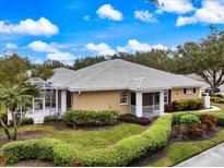 Tan one-story home with tile roof, screened lanai, and lush landscaping at 900 Paisley Ct # 1, Venice, FL 34293