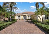 Beautiful yellow house with palm trees and a brick driveway at 1014 Tuscany Blvd, Venice, FL 34292