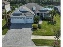 Single-story home with gray siding, three-car garage, and landscaped lawn at 12353 Auburndale Ct, Venice, FL 34293