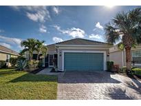 Single-story home with teal garage door, landscaping, and paver driveway at 19374 Rizzuto St, Venice, FL 34293