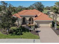 Tan one-story house with a tile roof, arched entryway, and landscaped yard at 298 Montelluna Dr, North Venice, FL 34275
