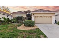 One-story home with tile roof, attached garage, and landscaped lawn at 320 Langholm Dr, Venice, FL 34293