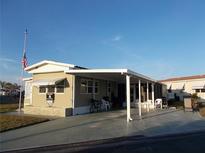 Tan mobile home with carport and American flag at 476 Boxwood Dr, Venice, FL 34285