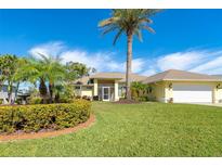 Bright yellow house with palm trees, lush landscaping, and a large driveway at 49 Perimeter Dr, Englewood, FL 34223