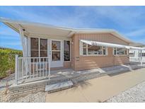 Tan single-wide manufactured home with white trim, covered porch, and landscaped walkway at 521 Roma Road, Venice, FL 34285