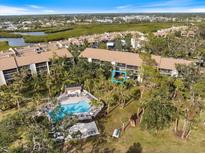 Aerial view of condo community showing building, pool, and surrounding landscape at 784 Bird Bay Way # 105, Venice, FL 34285