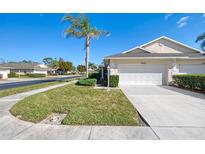 Exterior view of a single-story villa with a white garage door and landscaped lawn at 1102 Auburn Cove Cir, Venice, FL 34292