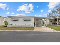 Single-wide mobile home with carport and landscaped yard at 115 White Oak Way, Sarasota, FL 34237