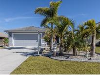 Gray house with attached garage,palm trees,landscaped yard at 4251 Oak Terrace Cir, Port Charlotte, FL 33953