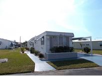 Mobile home with landscaped lawn, driveway, and carport at 426 Boxwood Dr, Venice, FL 34285